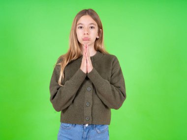 Yeşil süveter giyen güzel beyaz kız mutlu bir şekilde gülümsüyor. Müfettişten hoş haberler aldığına seviniyor. Avuçlarını bir arada tutuyor..