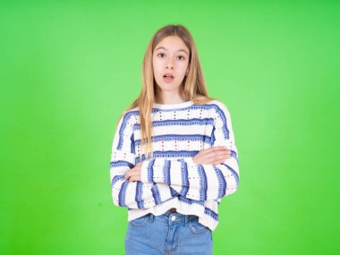 Utanmış, yeşil arka planda çizgili süveter giyen genç ve güzel bir kız ağzını açık tutuyor. İnanılmaz bir yenilik duyuyor sersemlemiş gibi bakıyor.