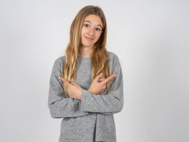 Gri eşofman giyen güzel beyaz kız kollarını kavuşturuyor ve farklı tarafları işaret ediyor. İki nesne ya da varyant arasında tereddüt ediyor. Karar vermede yardıma ihtiyacı var