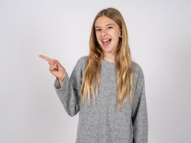 Gri eşofman giyen beyaz güzel bir kız fotokopi boşluğunda işaret ediyor. İnsanlar tanıtım ve reklam kavramları