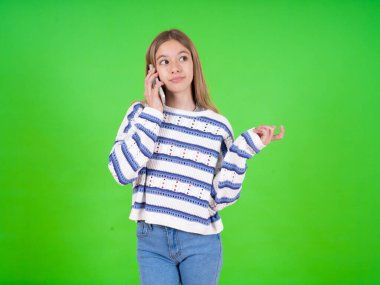 Yeşil arka plan üzerine çizgili süveter giyen güzel bir genç kız cep telefonuyla konuşuyor. Boş vakitlerini evde arkadaşlarıyla konuşarak geçiriyor..