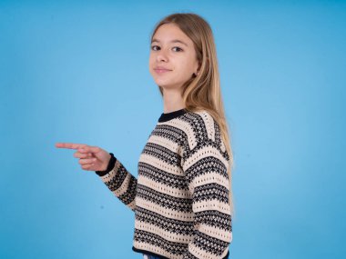 Mavi stüdyo arka planında çizgili süveter giyen güzel beyaz bir kızın profil fotoğrafı boş bir parmak teklifi olduğunu gösteriyor.