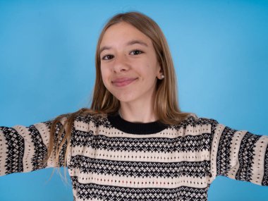 Mavi stüdyo arka planında çizgili süveter giyen güzel beyaz bir kızın fotoğrafı.