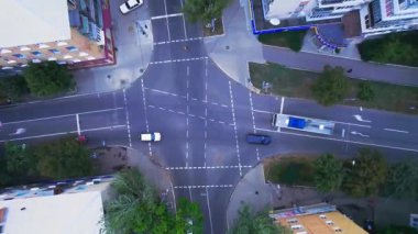 Bir kavşağın kuş bakışı görüntüsü. Video, kavşaktan geçen bir otobüs de dahil olmak üzere arabaların yanı sıra şerit ve yaya geçitlerini gösteriyor..