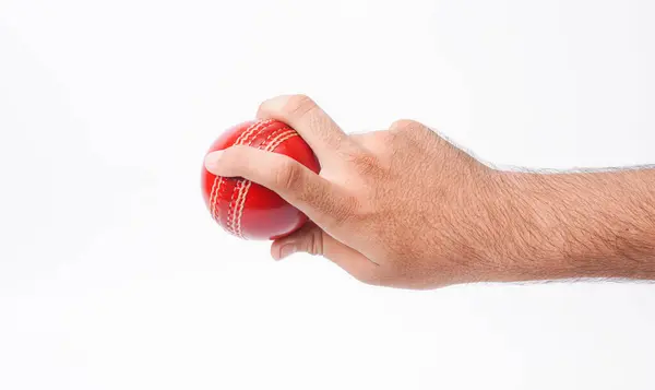 Stock image Closeup Photo Of A Male Bowler Firmly Gripping On A Red Test Match Cricket Ball On White Background