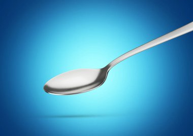 Uzatılmış sapı ve mavi arka planda yuvarlak kasesi olan Parlayan Metal kaşık.