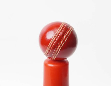 Kırmızı silindirik nesnenin tepesine yerleştirilmiş parlak, yeni bir kriket topu.