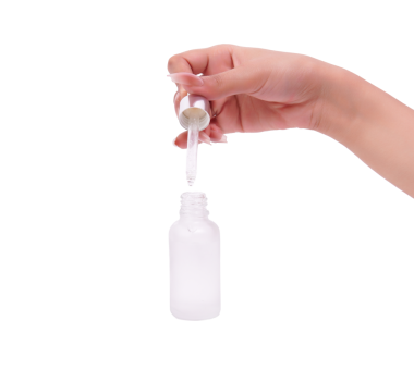 Cilt rutini için dondurulmuş kozmetik şişeye serumu atan el.