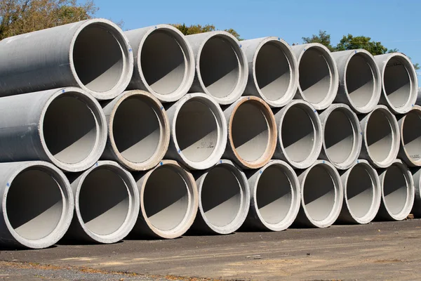 Stacked cement pipes at concrete factory, outdoors warehouse storage grey heavy material