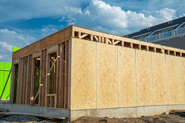 İnşaat ve mavi gökyüzü altında, ahşap kirişlerle, ahşap kirişlerle, ahşap çerçeveli ahşap kaplamalı eve yakın çekim.