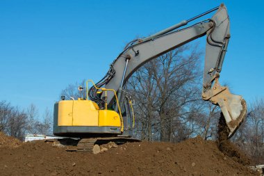 large crawler excavator pours a bunch of sand yellow heavy sky