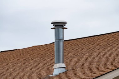 metal chimney on house roof, clean new shiny chimney pipe on blue sky background modern top