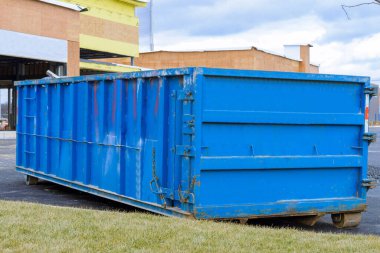blue dumpster, bin near new construction site of apartment houses building junk removal scrap