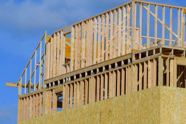 new construction home framing against blue sky wall woood truss lumber framework