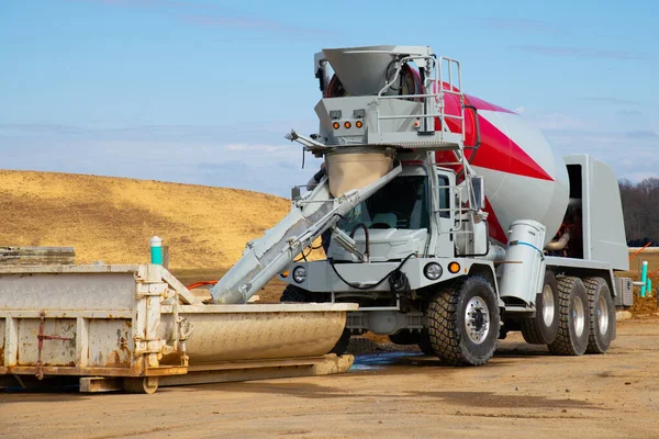 pouring concrete from automobile mixer into crane bucket truck heavy dump