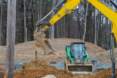 Kazıcı kanalizasyon suyu yükleyicisi için çukur kazıyor.