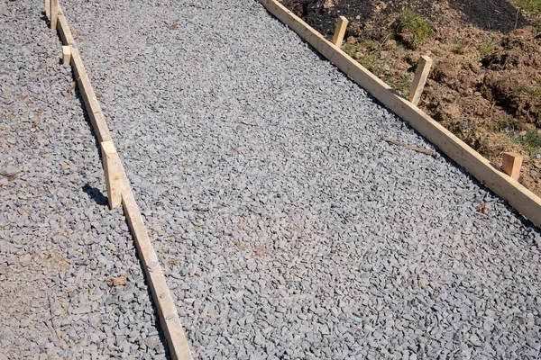 a sidewalk is under construction, a concrete curb is being installed and the foundation of the road is being prepared new gravel sand stone concrete new sunny