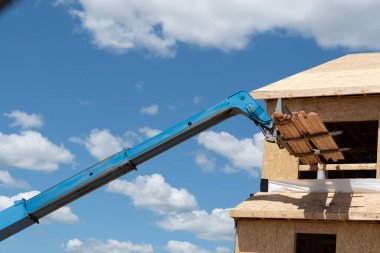 Kontrplak bir evin inşaat sahasında forklift. Yeni çerçeve vinç teleskopik materyalleri.