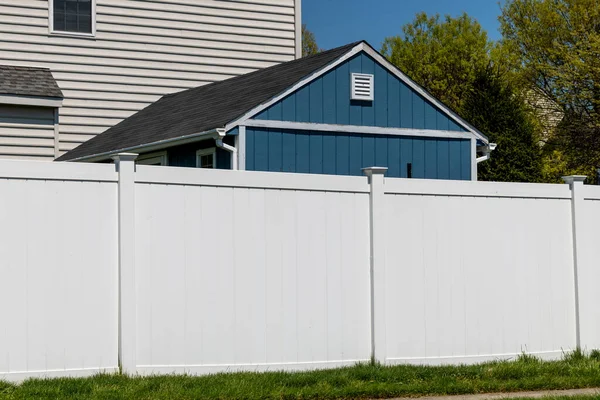 Bahçeyi çevreleyen yeşil çimenlikte bahçe koruması ve mahremiyet duvarı için beyaz vinil çit.