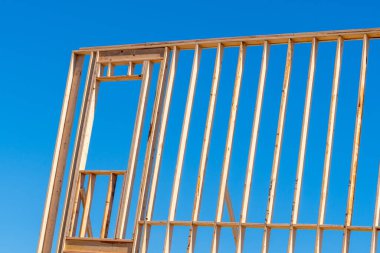 Mavi gökyüzü ahşap iskeletine karşı çerçevelenen yeni konut inşaatı evi