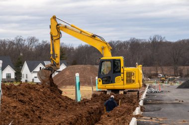 Kazıcı siper kazıyor, kürek çekiyor, traktör gücü sarı.
