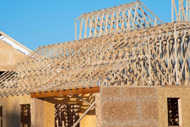 rafters of a plywood new house against a blue sky frame roof material clipart