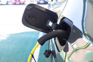 Elektrikli arabaya takılan kabloların ayrıntıları, bataryayı şarj ediyor. Sürdürülebilirlik, elektrik, yük, yenilenebilir enerji.
