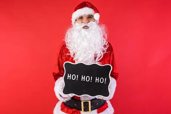 一个人穿着圣诞老人的衣服 拿着一个黑色的标牌 上面写着 红色的背景 圣诞节 消费主义和幸福概念 — 图库照片