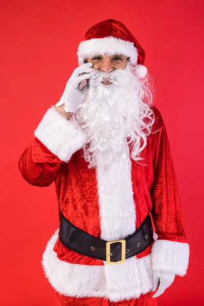 男人穿得像圣诞老人 在手机上用红色背景说话 圣诞节 消费主义和幸福概念 — 图库照片