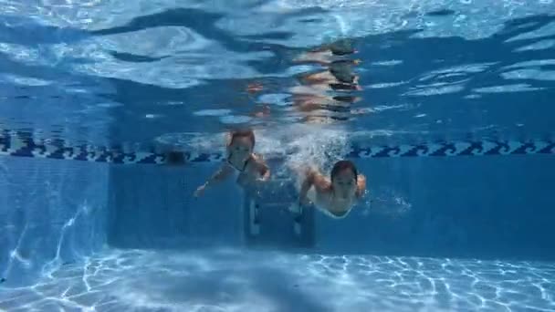 两个女孩跳进游泳池 对着摄像机挥手 童年时代 游泳池及游泳的概念 — 图库视频影像