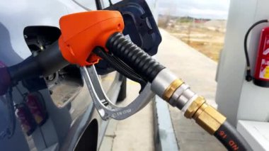 Benzin istasyonundaki bir arabaya LPG otogaz hortumunu takar ve biriken benzini patlatır. Benzin, dizel, sıvılaştırılmış benzin, LPG, galon, süper, kriz, pahalı ve ulaşım.