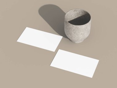 Yumuşak, minimalist ışıklandırmalı pürüzsüz bir yüzeyde iki kartvizit..