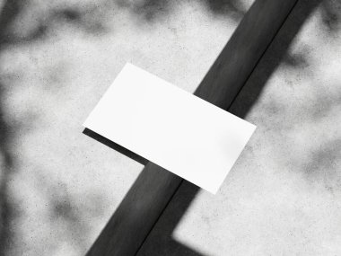 Yumuşak ışıklandırmalı beton yüzey üzerine zarif bir kartvizit sunumu.