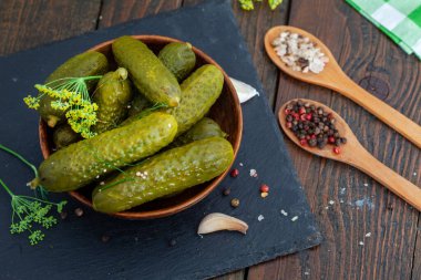 Bir kase lezzetli salatalık turşusu baharatlı ve ahşap masada dereotlu. Terbiye edilmiş ev yapımı salatalık turşusu. Sağlıklı mayalanmış yiyecekler.