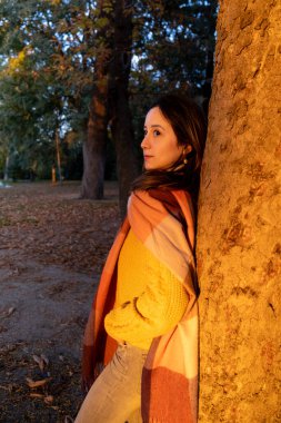 Şehir parkında sonbahar günbatımının tadını çıkaran genç bir kadının portresi.