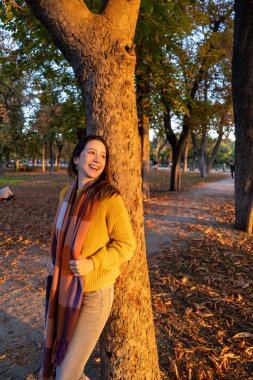 Şehir parkında sonbahar günbatımının tadını çıkaran genç bir kadının portresi.