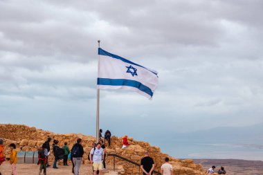 Judaean Çölü, Güney Bölgesi, İsrail - 10 Nisan 2023. Masada Ulusal Parkı 'nda turistler ve İsrail bayrağı.