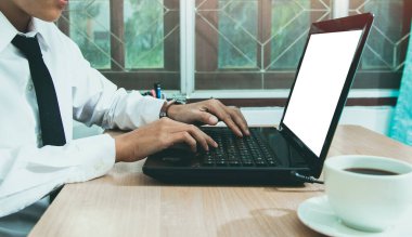Başkanlık araştırma kursunun internet sitesinde oturan ve ev konseptinde beyaz ekran laptopundan öğrenme, e-öğrenme eğitimi alan insanlar. Masanın üzerinde bir fincan kahveyle