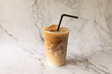Beyaz mermer arka plan fotoğrafında plastik bardakta buzlu latte kahve..