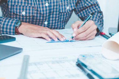 Mühendisler ofiste dizüstü bilgisayarı olan planlar üzerinde çalışıyorlar. Konsept mimarlar evden çalışır
