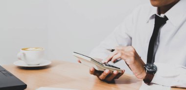 business Asian woman using calculator calculating digital money looking graphs cryptocurrency trading platforms on a laptop and coffee on the desktop table at the home office in the morning.