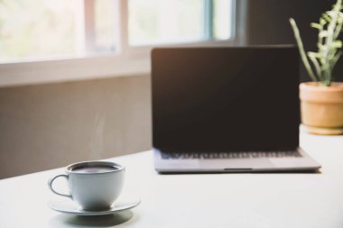 White of aroma coffee cup on the table with laptop ready to work for drink caffeine working home office in the morning, Energy drink before starting work concept. close up