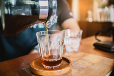 Close up hand of barista pouring, dripping coffee into the glass with equipment tool brewing table on the morning.