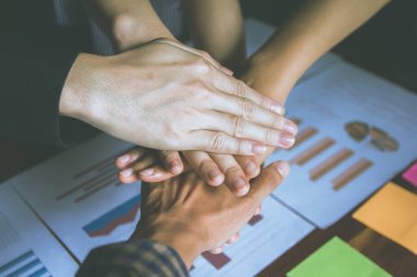 Asyalı iş adamları ellerini bir araya getirdi. El ele tutuşmak. Birliğin karşılıklı fayda sağlayan bir iş ilişkisi. Ekonomi grafiği masada. Takım çalışması konsepti