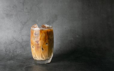 Buzlu latte kahveyi şeffaf bardağa koyup siyah arkaplanlı stüdyo fotoğrafına buzlu kahve koyarız. Dört metin kopyala