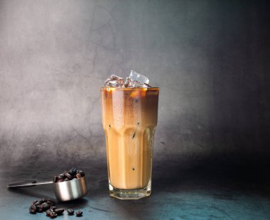 Buzlu latte kahve şeffaf bardakta buzlu olsun. Ve siyah arkaplan fotoğrafında kahve çekirdekleri kavurması.