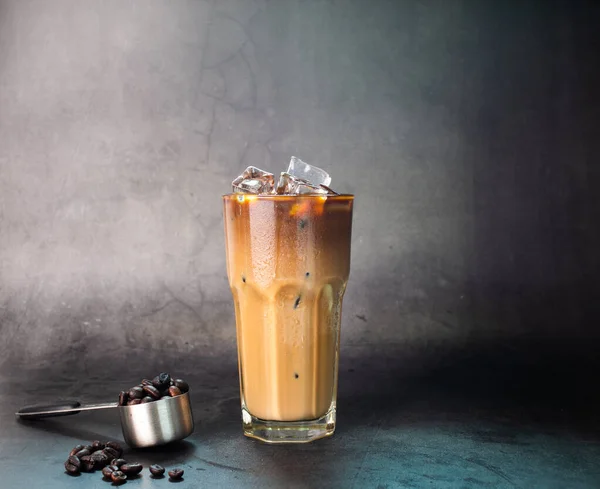 Buzlu latte kahve şeffaf bardakta buzlu olsun. Ve siyah arkaplan fotoğrafında kahve çekirdekleri kavurması.