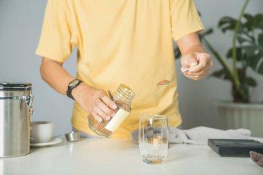 Kahveci hazır kahve tozu koyuyor bardağa sıcak kahve yapıyor. Mutfaktaki ahşap barın üzerinde dijital bir aletle. Evde kahve yap.