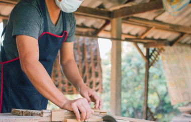 Asyalı marangoz fabrikasında bir masa masasının üzerine bir kutu yapmak için dairesel testere kullanıyor. Ev konseptinde kendi patronun olarak çalışıyorsun.