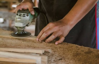 Asyalı marangoz fabrikasındaki tezgahın ahşap yüzeyini pürüzsüz hale getirmek için elektrikli odun zımpara makinesi kullanıyor. Küçük işletme, evde kendi patronun olarak çalışmak.